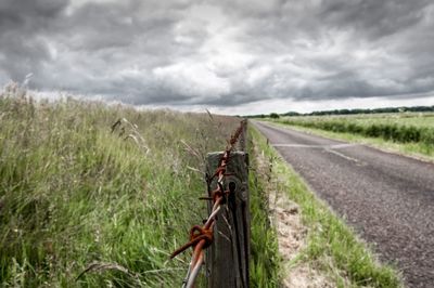 View of field against cloudy sky