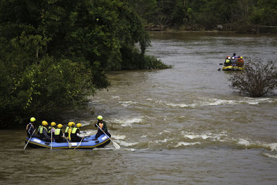 People in boat on river against trees