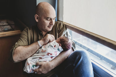 Father holding newborn boy wrapped in blankets in hospital