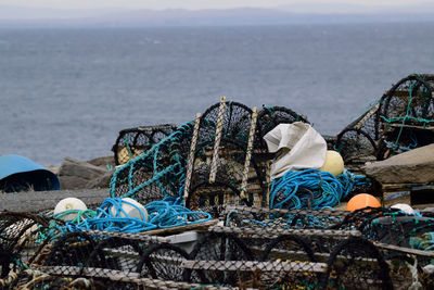 Stack of fishing net by sea against sky