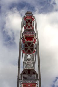 Low angle view of ferris wheel against cloudy sky