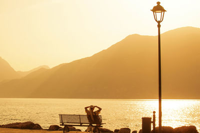 A girl on the shore of lake garda admires the sunset