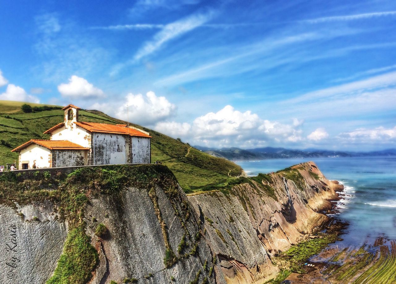 sky, built structure, building exterior, architecture, cloud - sky, blue, rock - object, tranquil scene, tranquility, cloud, scenics, nature, beauty in nature, landscape, religion, plant, spirituality, hill, day, outdoors