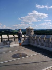 Full length of woman standing against blue sky