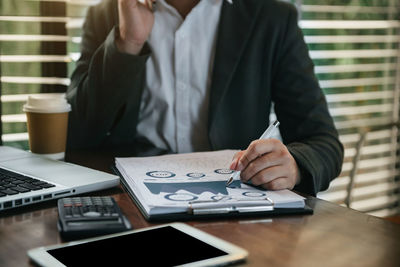 Midsection of man using mobile phone on table