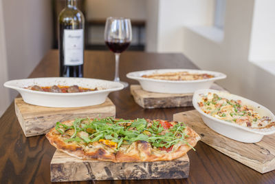 An array of italian dishes lay on a table with a bottle of red wine