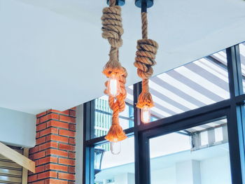 Low angle view of light bulbs with ropes hanging from ceiling