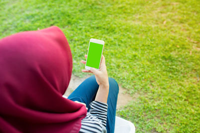 High angle view of woman wearing hijab using mobile phone while sitting in park