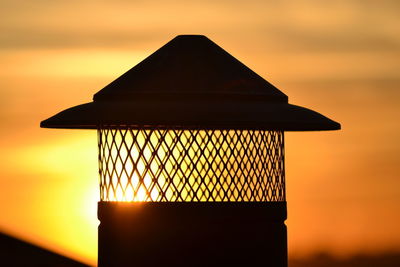 Close-up of orange lamp against sky during sunset