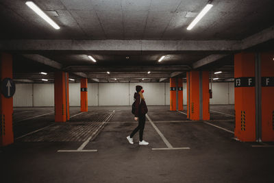 Woman with facial mask walking in empty garage parking