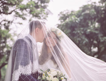 Groom kissing smiling bride under veil