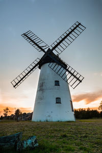 Traditional windmill on field against sky at sunset