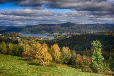 Scenic view of field by river against sky