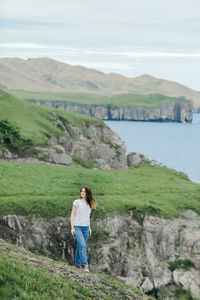 Girl dark hair in a white t-shirt and jeans conquers mountains, beautiful mountainous high landscape