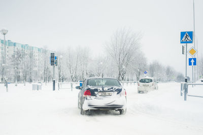 Cars on snow covered road against sky