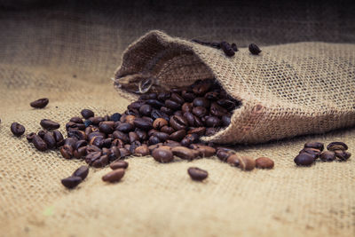 Close-up of roasted coffee beans spilling from burlap