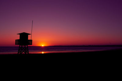 Silhouette of a beach watchtower in front of the sunset