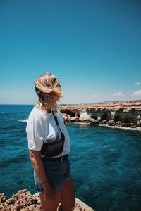 Woman looking at sea against blue sky