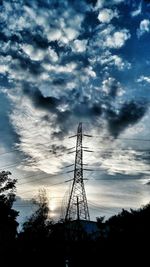 Low angle view of electricity pylon against cloudy sky