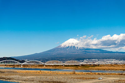 Scenic view of lake by mountains against blue sky