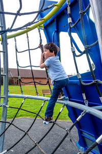 Full length of boy climbing on jungle gym at playground