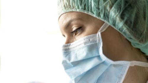 One woman, worried female doctor in protective suit, looking through the hospital window