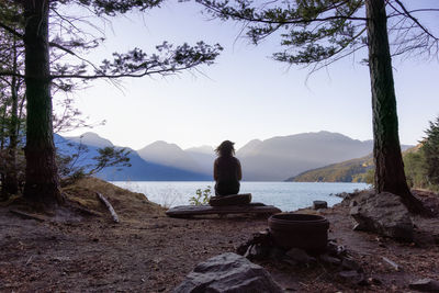 View of sitting on tree trunk by mountain against sky