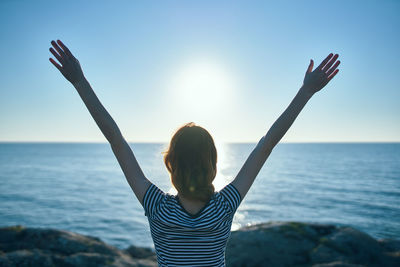 Rear view of woman standing in sea against sky