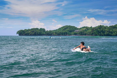 Surfer in sea against sky batu karas, pangandaran west java