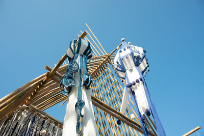 Low angle view of crane by building against clear blue sky