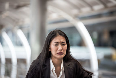 Close-up of young woman frowning outdoors