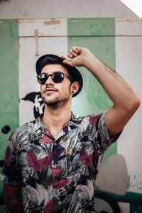 Handsome young guy with sunglasses touching his hat person