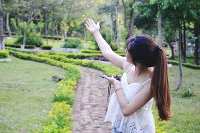 Woman with arms raised standing at park