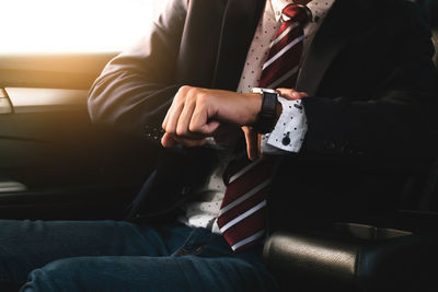 Midsection of man checking time while sitting in car