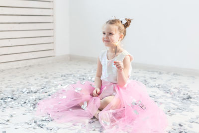 Portrait of girl sitting on pink wall