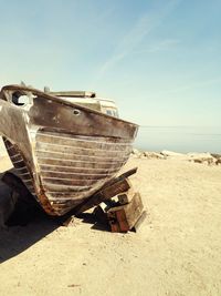 Old boat moored at beach against sky