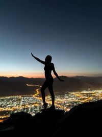 Silhouette woman standing on mountain against sky during sunset