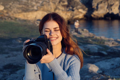 Portrait of smiling young woman standing against water