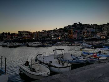 Boats moored in harbor against buildings in city