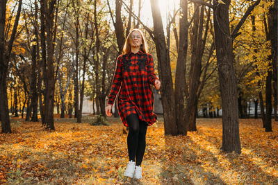 Full length portrait of young woman in forest during autumn