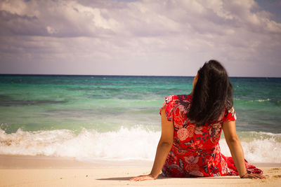 Rear view of woman at beach against sky