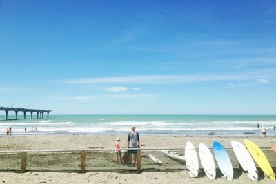 Rear view of man and daughter at beach against sky