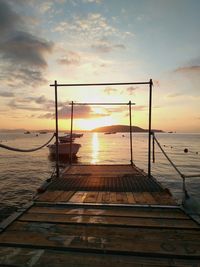 Jetty in sea against sunset sky