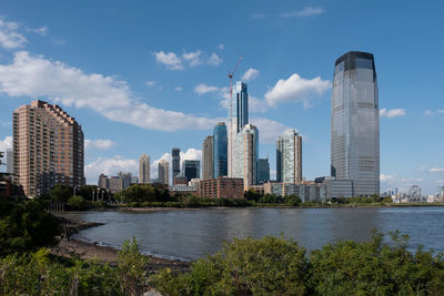 Buildings by river against sky in city