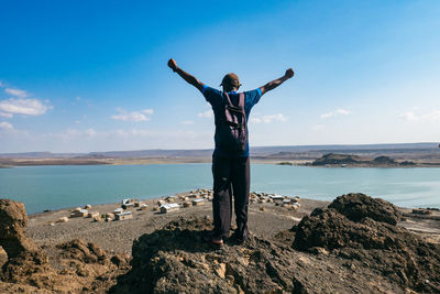 Rear view of a man standing on a rock against the background of el molo villagei, kenya