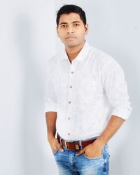 Portrait of young man standing against white wall