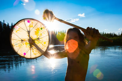 Reflection of woman on water in lake against sky