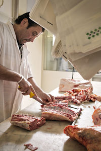 Serious butcher chopping pork rib at counter in shop