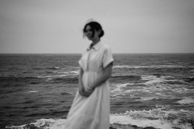 Woman standing at beach against sky