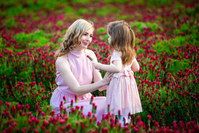 Mother and daughter amidst pink flowers